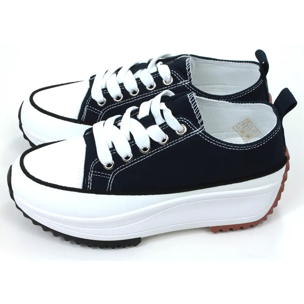 Lace up platform trainers in navy blue. White trim around the base above the black soles. White toe caps. Fabric shoe bodies. Navy blue pull on tabs at the ankles. White stitching detail. Side view.