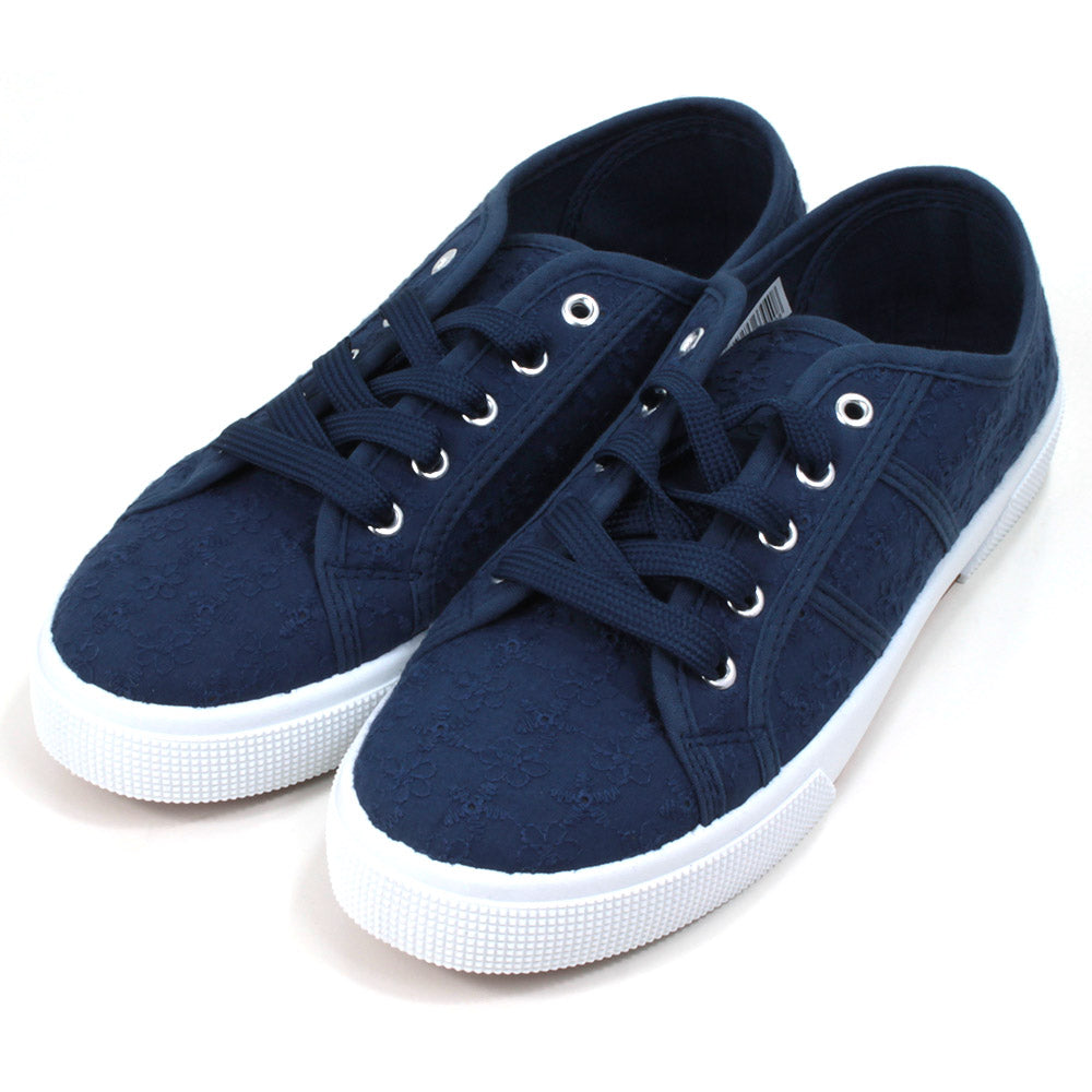 Navy blue plimsol style shoes with flat navy laces with 5 eyes. White rubber soles extending up the sides. Angled view. 