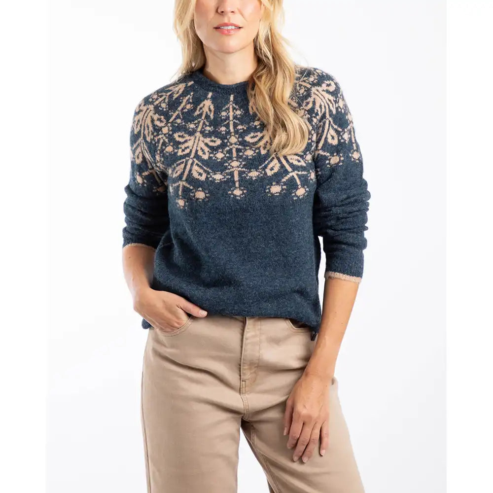 Woman wearing a blue sweater with a pattern, standing against a white background