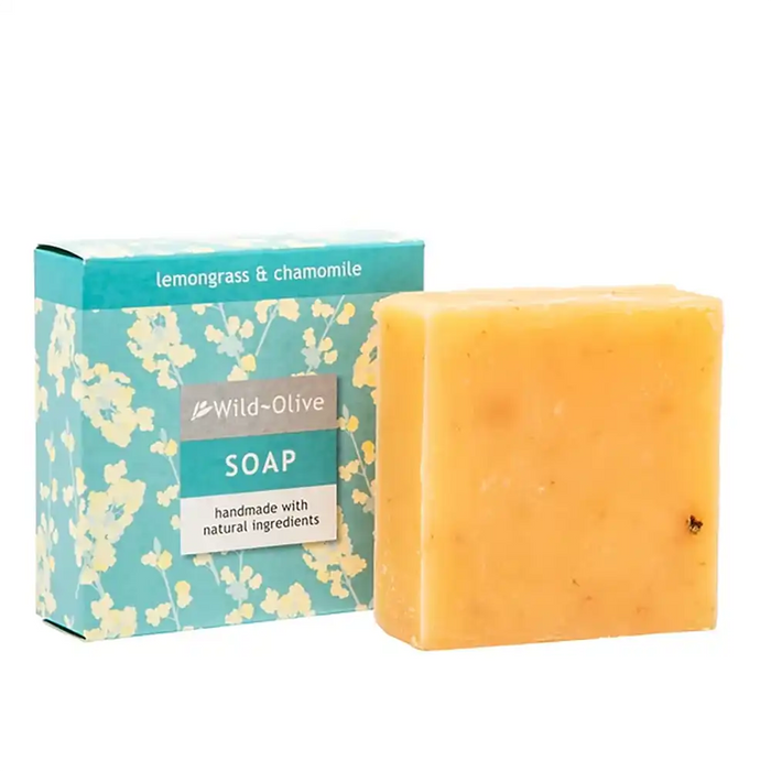 A 100g square bar of Wild-Olive soap in a warm yellow-orange colour stands in front of its teal and white floral packaging box on a plain white background.