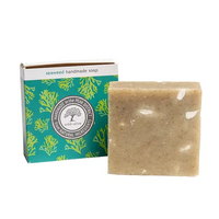 A rectangular bar of handmade seaweed soap in a speckled beige tone, shown next to its teal and white retail box with green seaweed illustrations. The box reads 'seaweed handmade soap'.