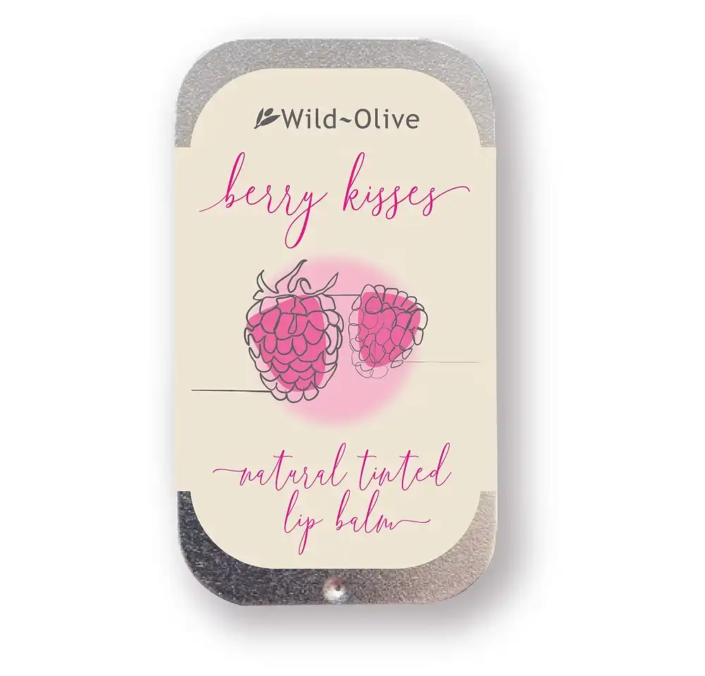 Wild-Olive Berry Kisses natural tinted lip balm in a silver metal tin with a cream-colored label featuring pink raspberry illustrations and pink script text.