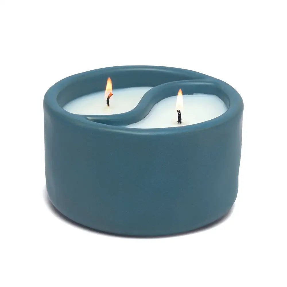 Blue ceramic candle holder with two lit candles on a white background