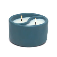 Blue ceramic candle holder with two lit candles on a white background