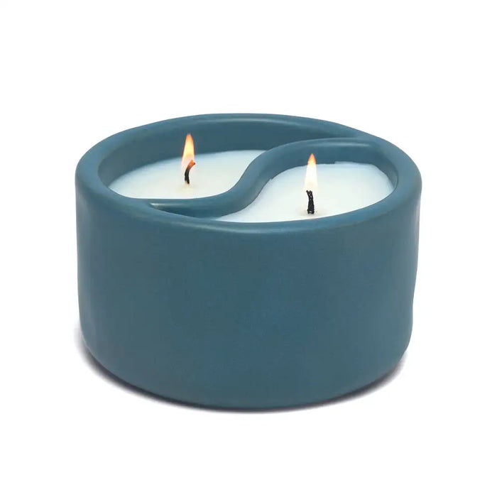 Blue ceramic candle holder with two lit candles on a white background