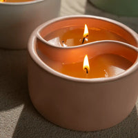 Candle in a wavy container with flames on a neutral background