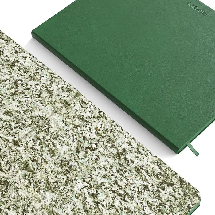 Green notebook on a white surface with a textured green lining beside
