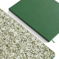 Green inner lining of a notebook on a white surface with a textured green front cover. 