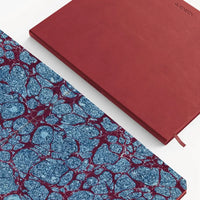 Two notebooks, one with a red cover and the other with a blue and red marbled pattern, on a white background.