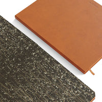 Two notebooks, one brown and one with a textured black cover, on a white background.
