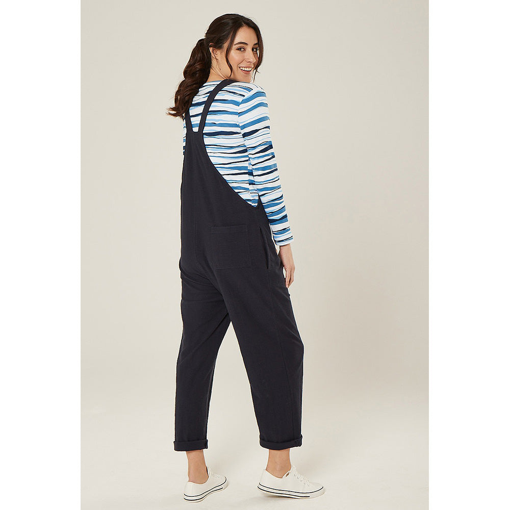 Adini Lucie dugarees in navy blue. Side pockets. Bib is fastened with knots in the straps. Leg length is on the ankle with turn ups. Showing back of garment.
