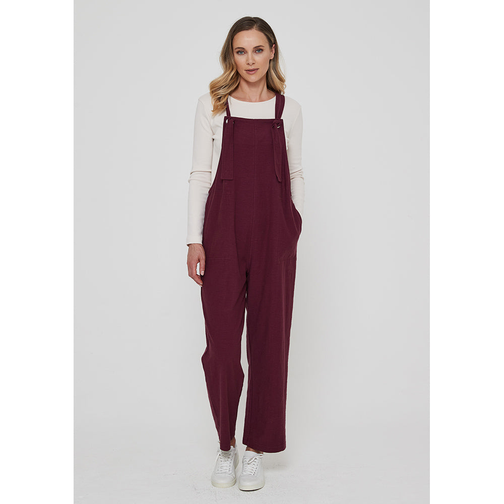 Adini Lucie dungarees in plum colour. Side pockets. Bib is fastened with knots in the straps. Leg length is on the ankle.