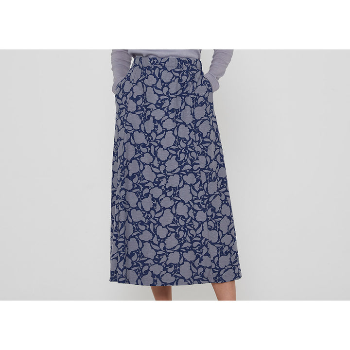 Adin Penzance skirt with grey blue flower silhouette pattern on navy blue background. Two pockets. Calf length. Close up of  garment.