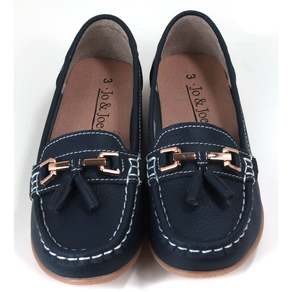 Joe and Jo Nautical moccasin slip on style shoes in dark blue. Gold decorative buckle with double tassels. White stitching. Rubber soles. Front view.