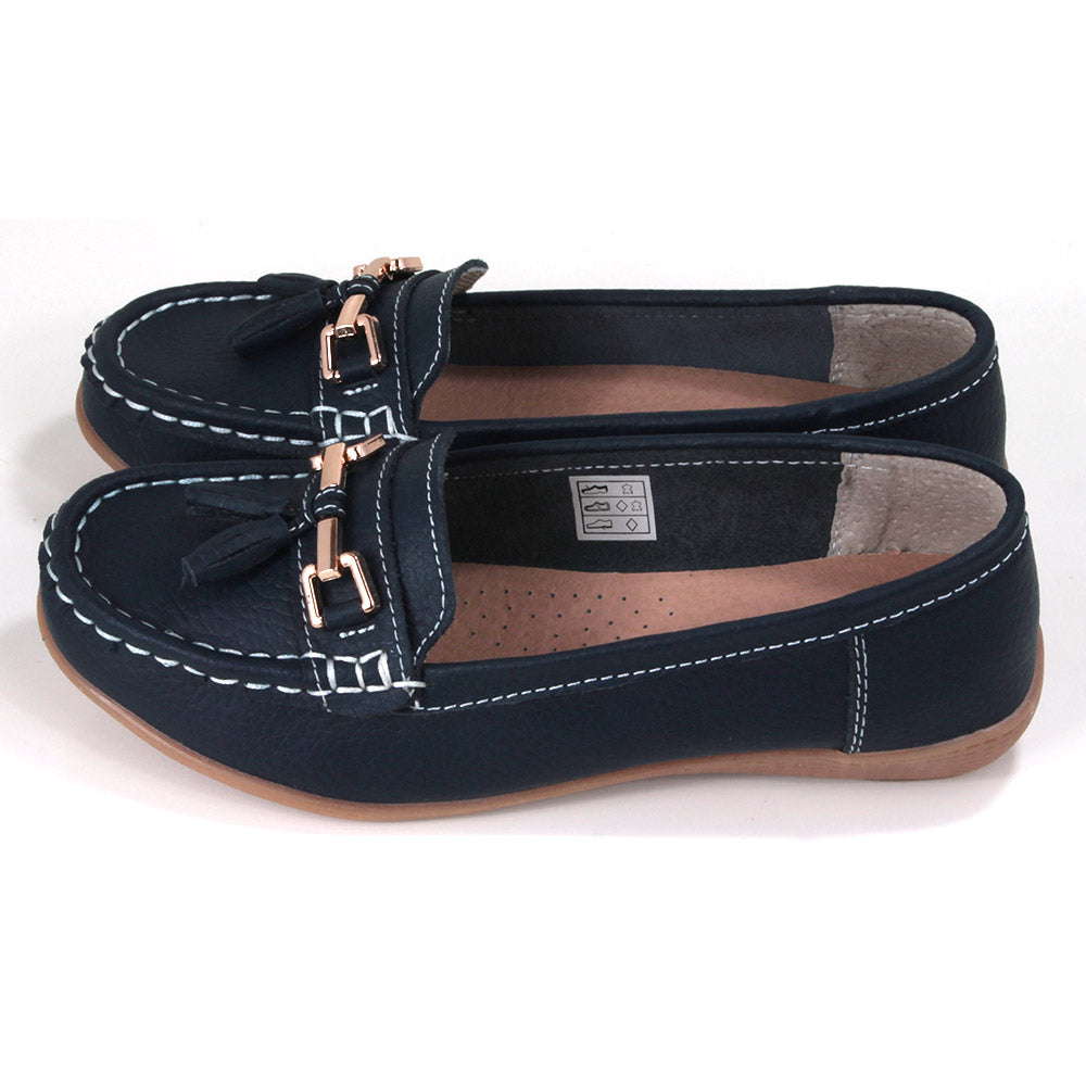 Joe and Jo Nautical moccasin slip on style shoes in dark blue. Gold decorative buckle with double tassels. White stitching. Rubber soles. Side view.