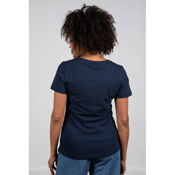 Model with dark curly hair wearing Lily & Me navy blue V neck tee shirt with short sleeves. Back view.