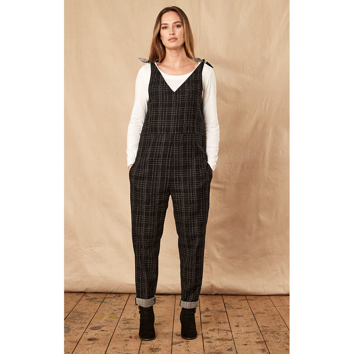 Nomads black checked jumpsuit with trouser turn-ups and secured by tied shoulders. Front view.