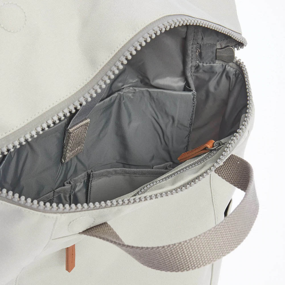 Roka light grey backpack. Close up of main compartment zip open showing internal pockets.